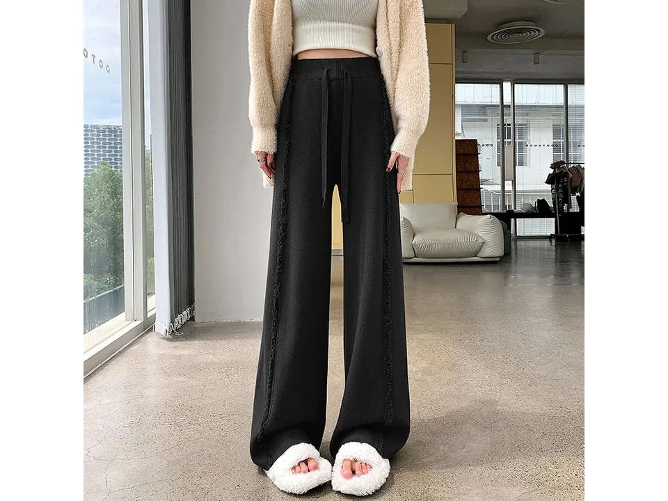 Full-length view of black high-waisted knitted trousers.