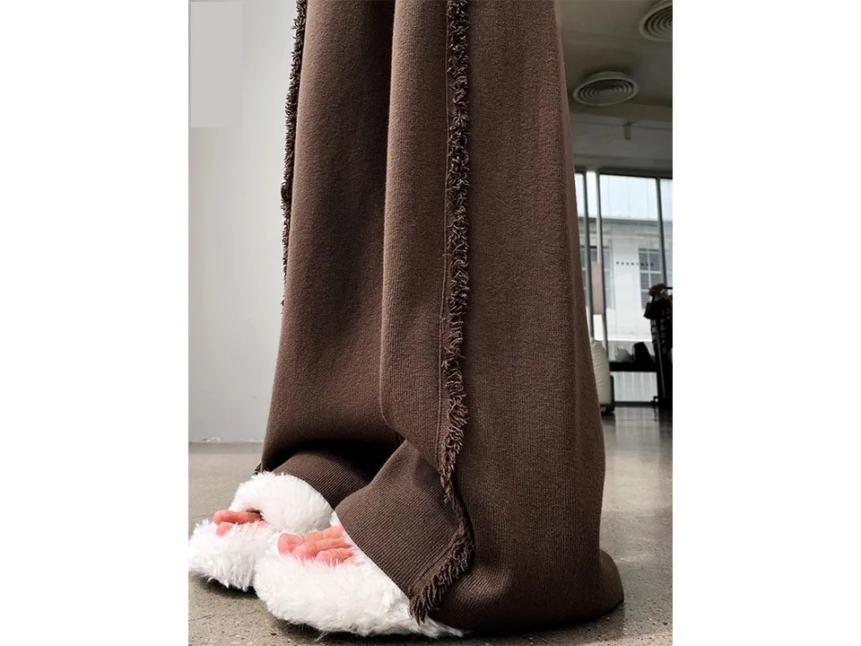 Close-up of brown knitted trousers with fringed side detail.