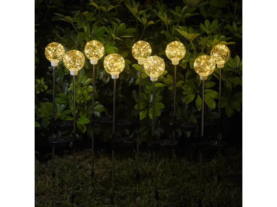 Multiple solar ball lights glowing in a garden at night.