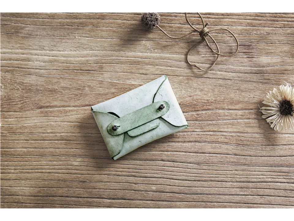 Green leather card holder on a wooden surface.