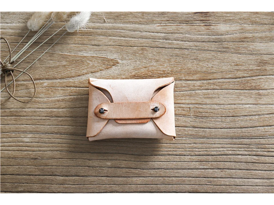 Light tan leather card holder on a wooden surface.