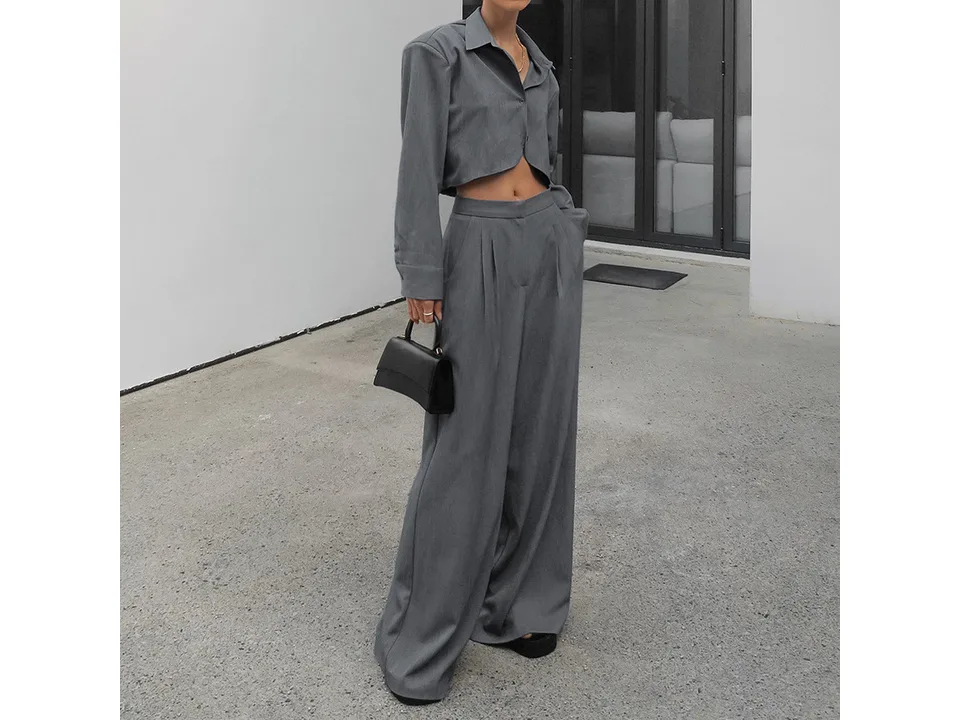 A model wearing the grey long sleeve crop shirt and wide leg trousers set.