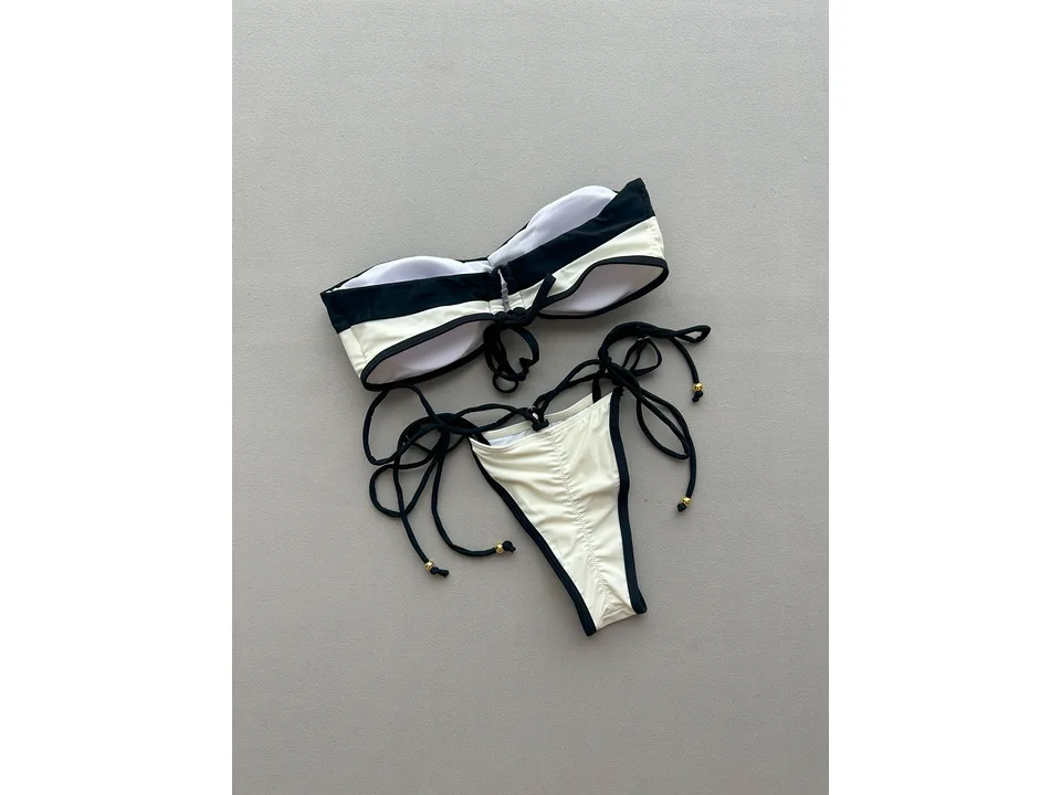A black and white bikini set laid flat on a grey background.