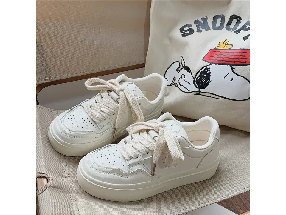 A pair of white casual low-top sneakers with a small flower detail on the side.