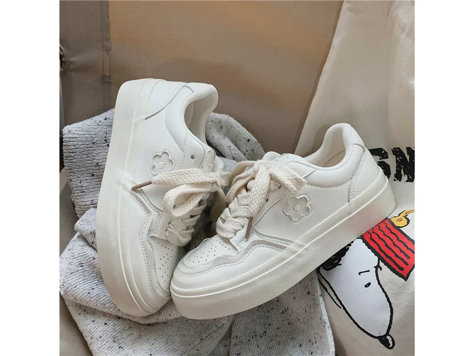 A pair of white casual low-top sneakers resting on a soft fabric.