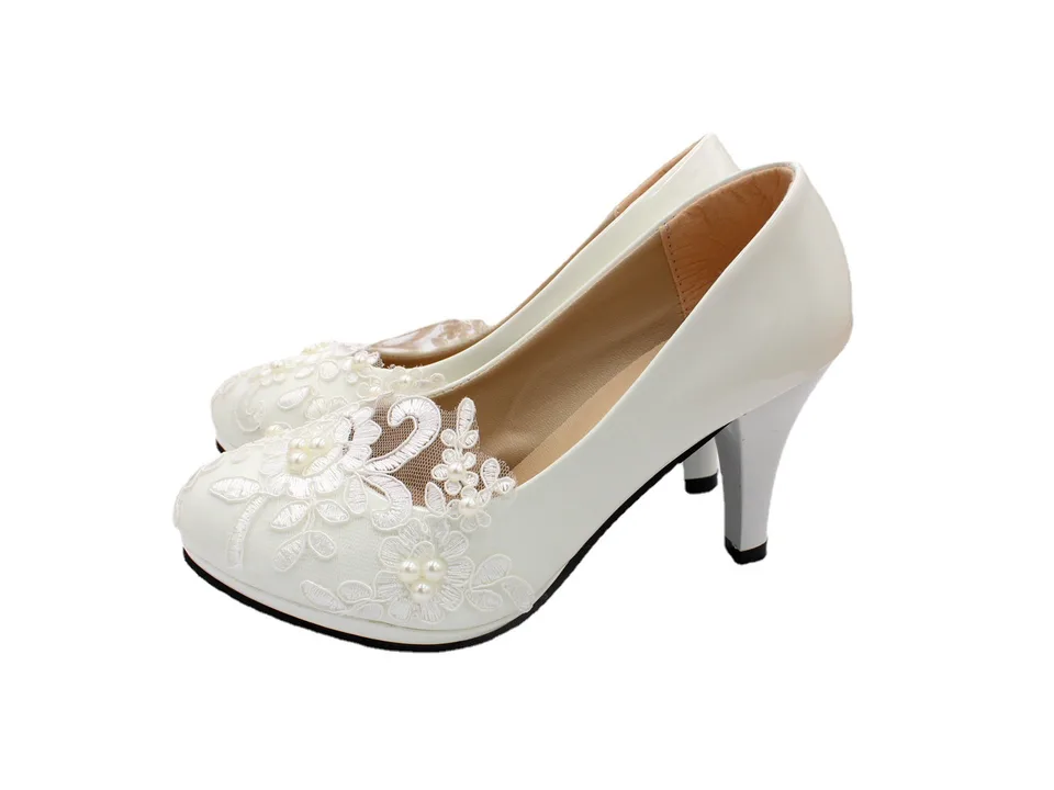 Side view of a white lace wedding shoe with a small heel.