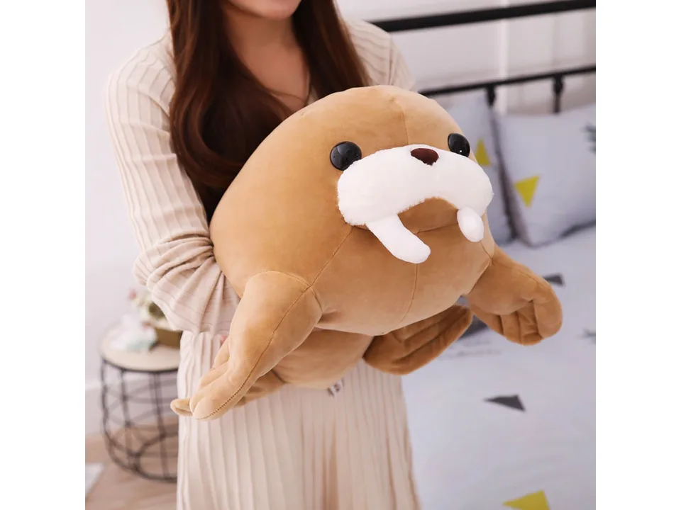 A person holding the brown walrus plush toy in their arms.