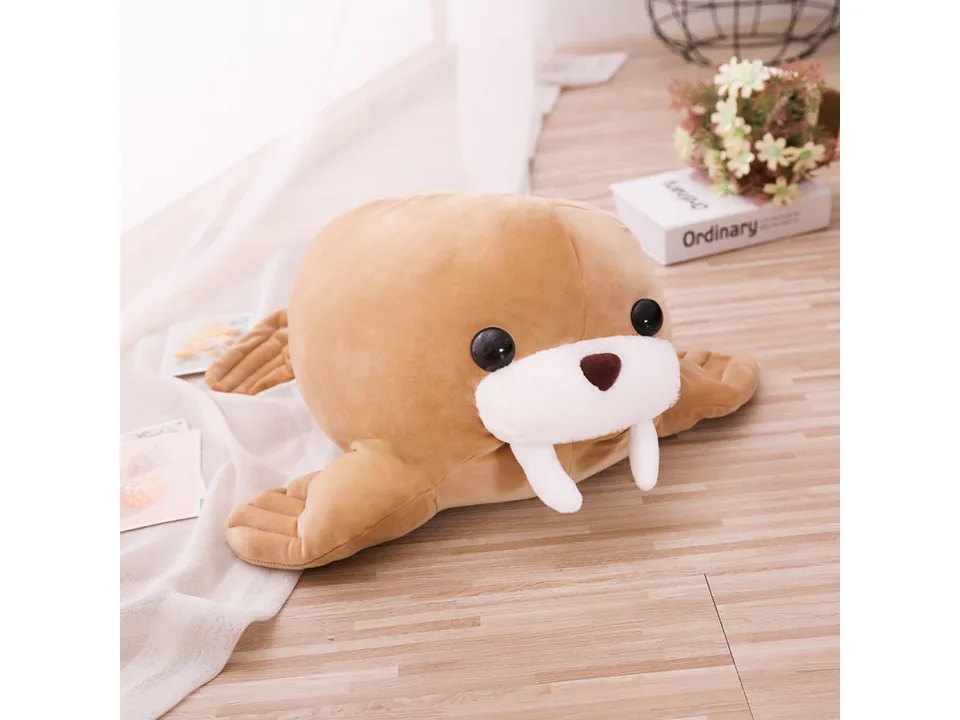 A brown walrus plush toy sitting on a wooden floor.