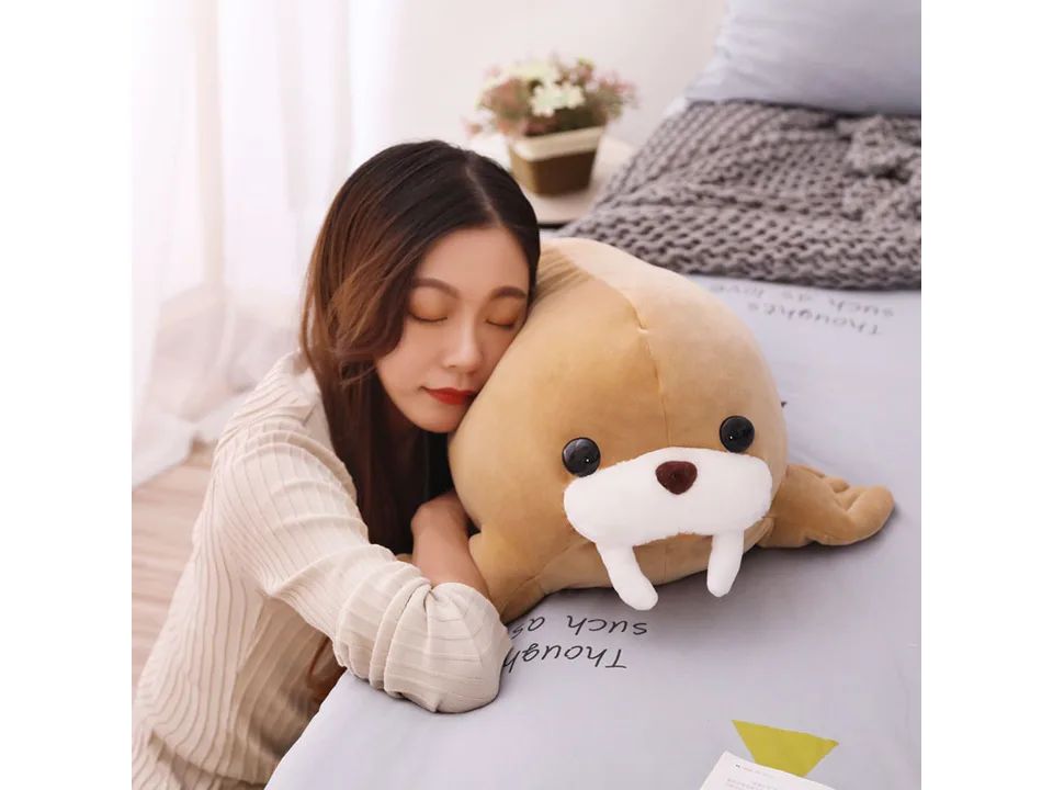 A woman cuddling the soft brown walrus plush toy.