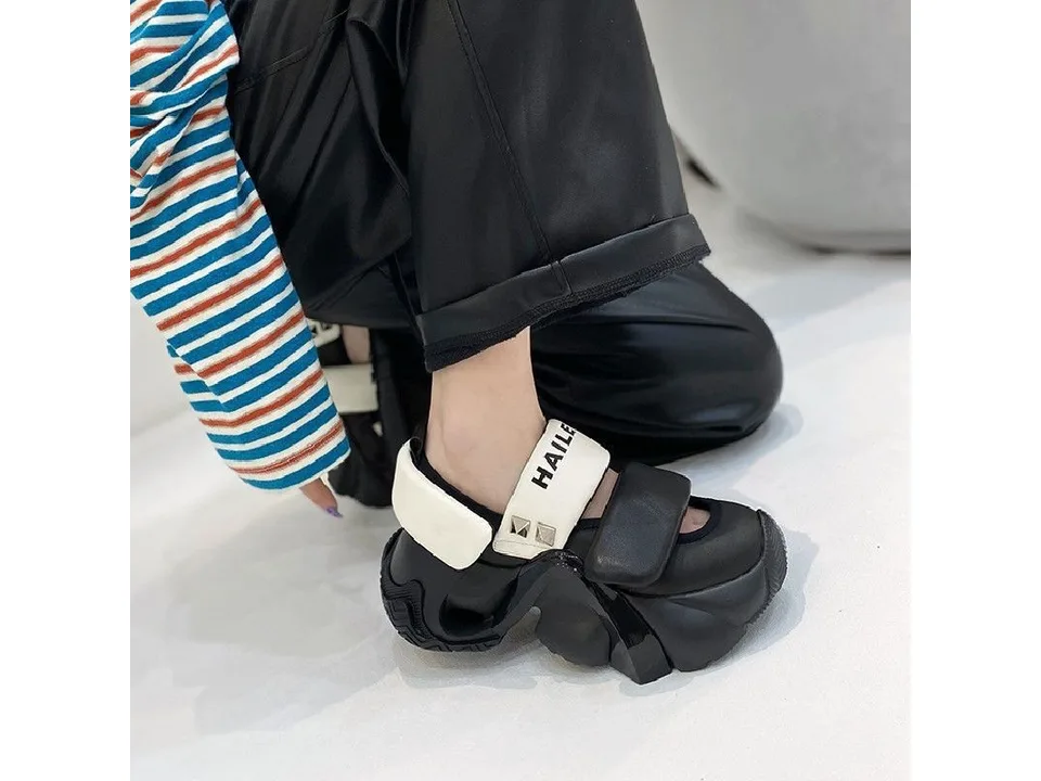 Side view of a person wearing black thick-soled sandals.