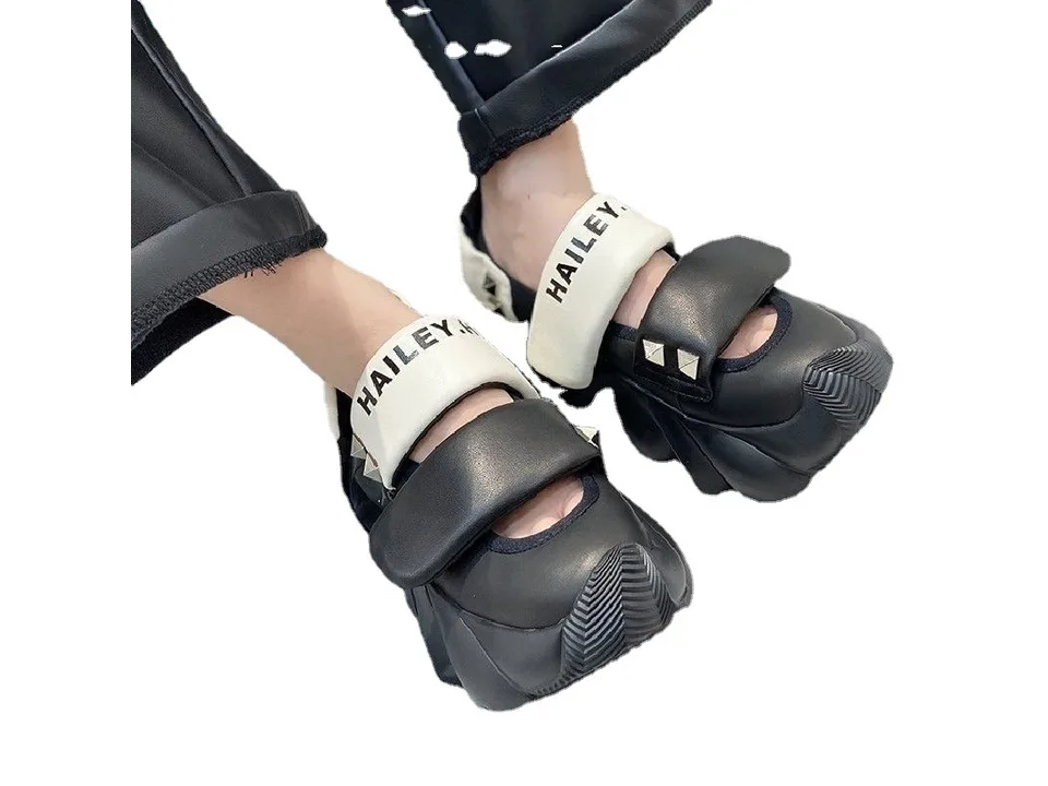 A pair of black thick-soled sandals worn on feet.