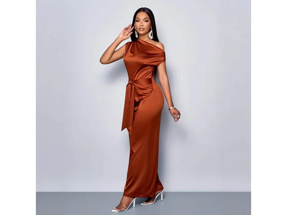 Model wearing the rust-colored one-shoulder jumpsuit with a tie waist.