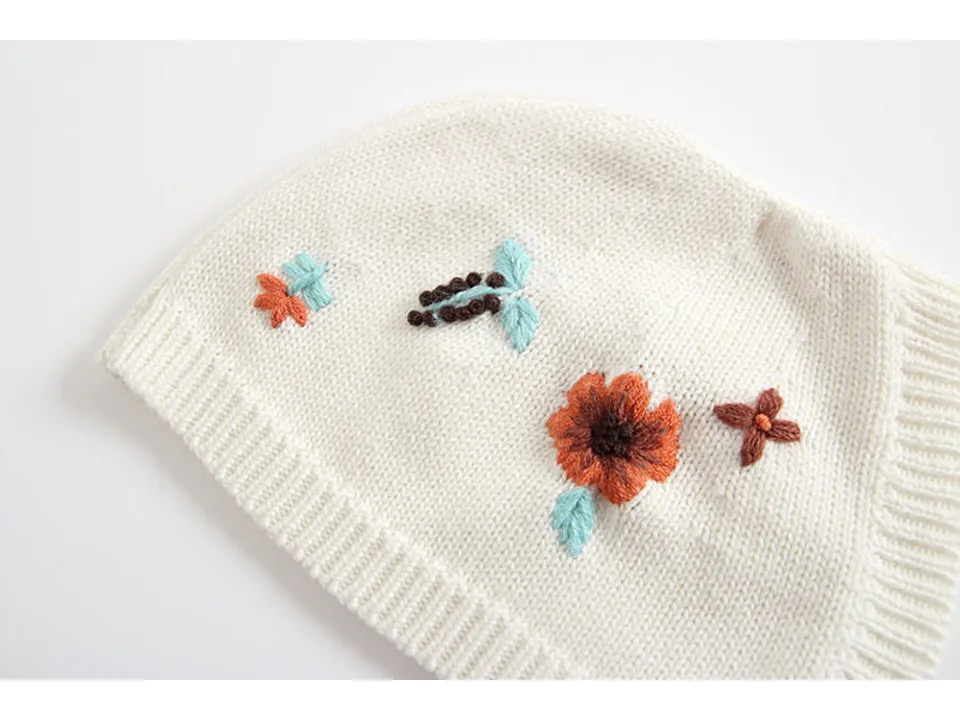 Close-up of the floral embroidery on the knit bonnet.