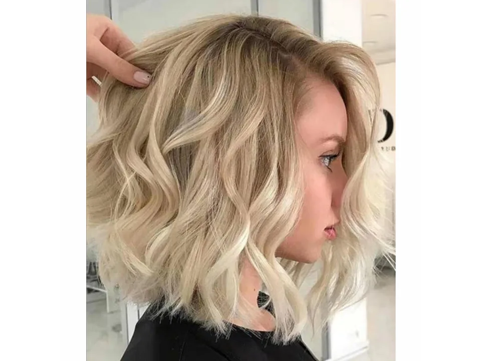 A woman wearing a short, wavy blonde wig.