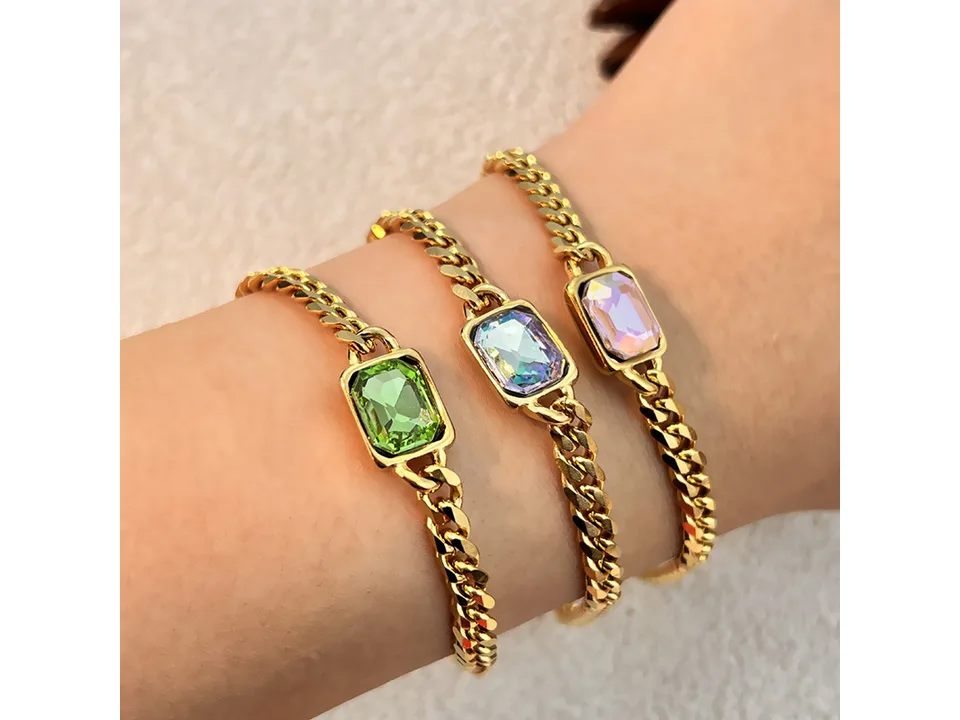 Three gold chain bracelets with rectangular gemstones worn on a wrist.