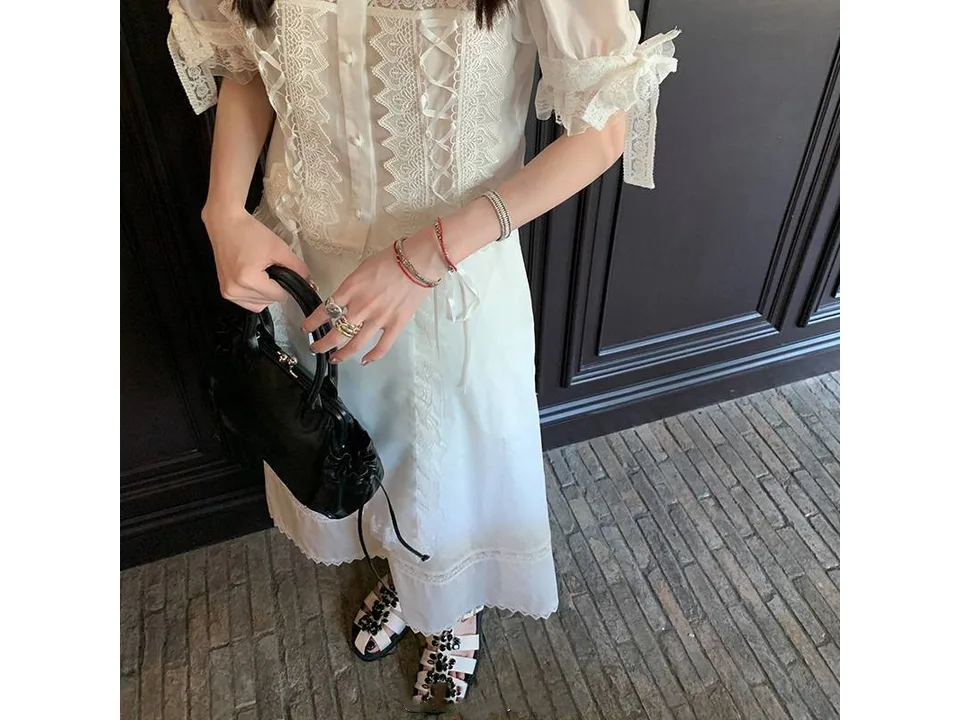 A woman wearing white rhinestone sandals with a white dress.