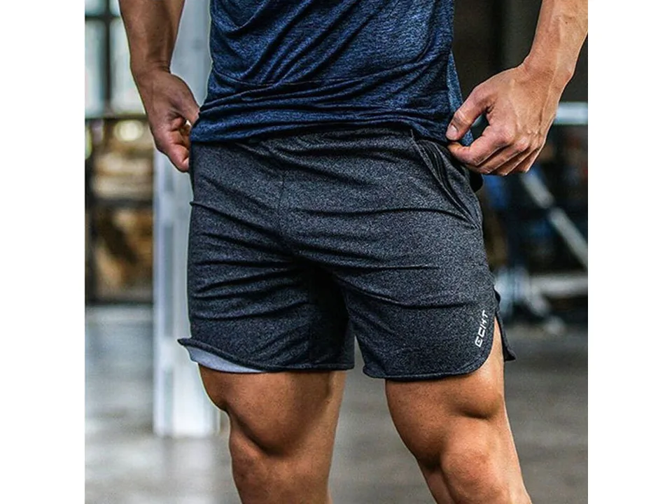 A man in a gym wearing dark grey athletic shorts.