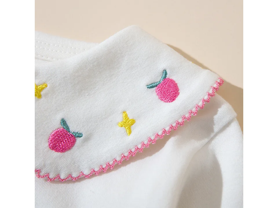 Close-up of the pink embroidered collar detail on the white shirt.