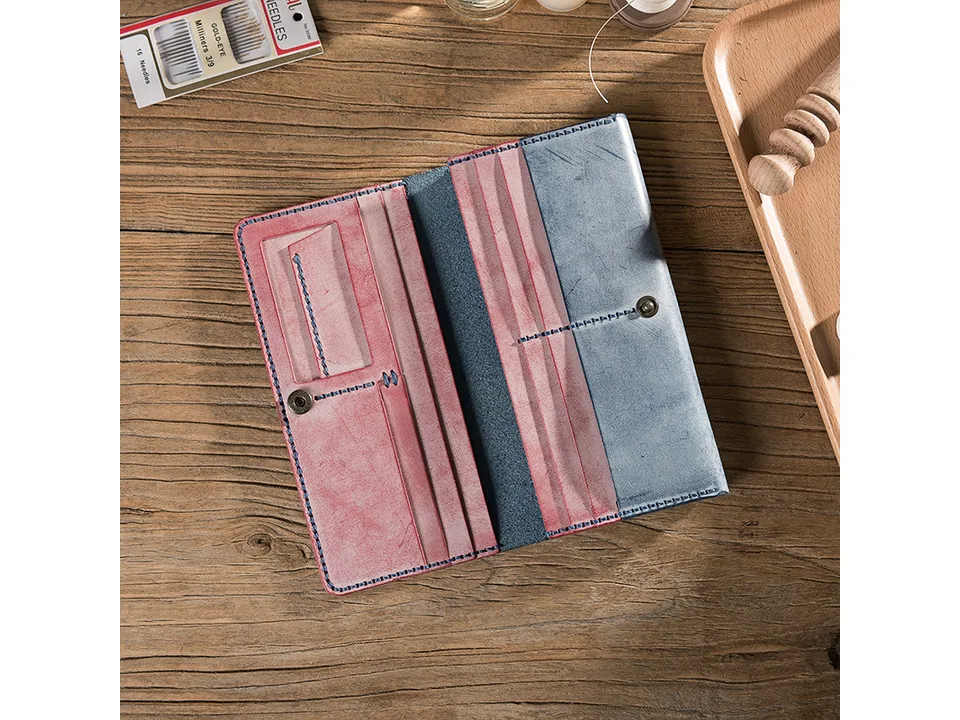 A finished handmade long leather wallet lying open on a wooden table.