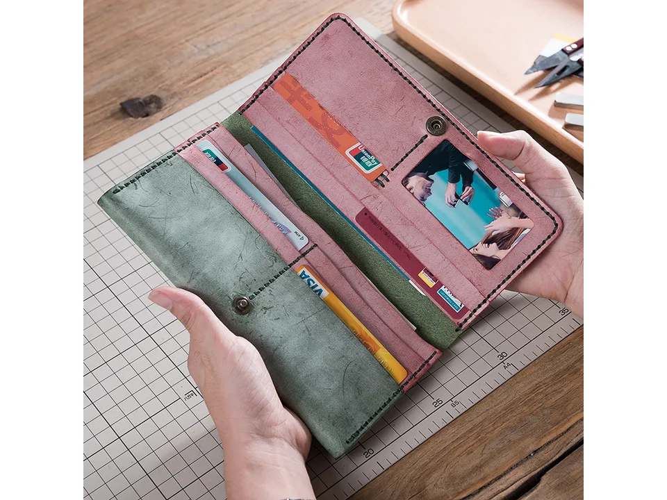 A person holding an open handmade leather wallet filled with credit cards and a photo.