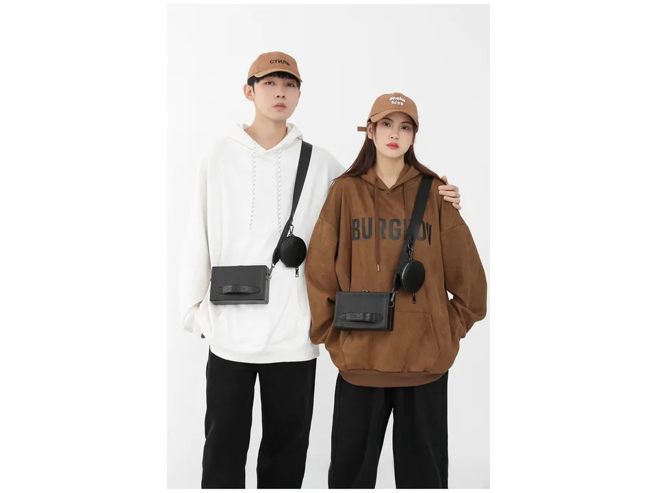 A man and a woman wearing the black crossbody messenger bag with a small detachable coin purse.