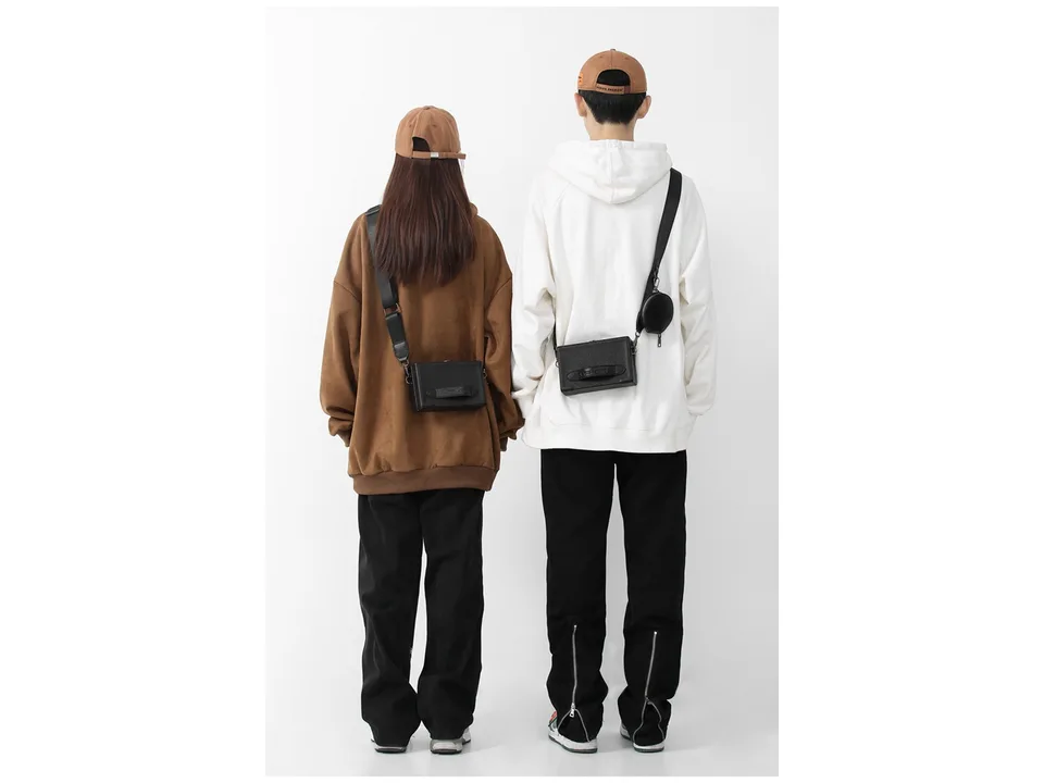 Rear view of a man and woman wearing the black crossbody messenger bag.