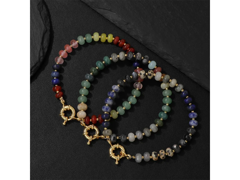 Three different styles of stone bead bracelets arranged on a dark surface.