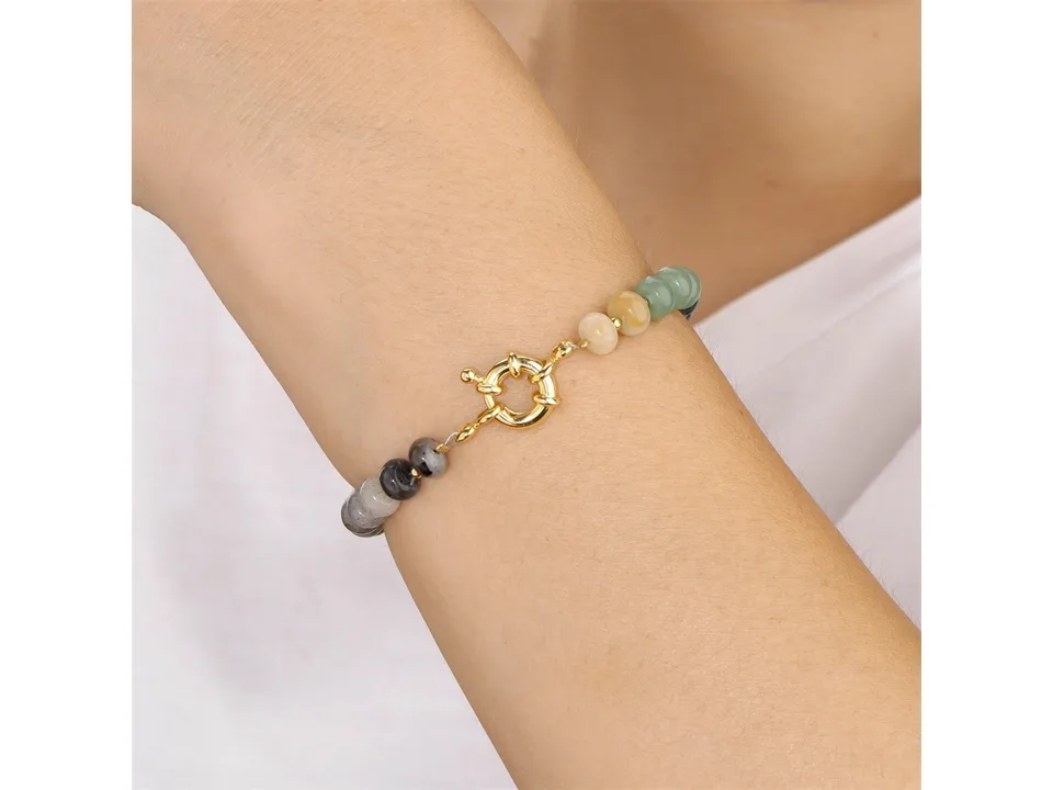 A multi-colored stone bead bracelet with a gold clasp worn on a wrist.