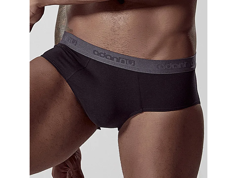 A man wearing black low-rise cotton briefs with a grey elastic waistband.