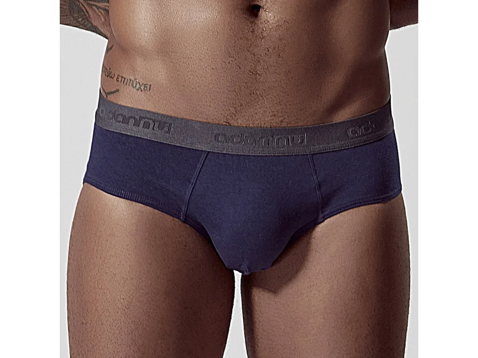 A man wearing navy blue low-rise cotton briefs with a grey elastic waistband.