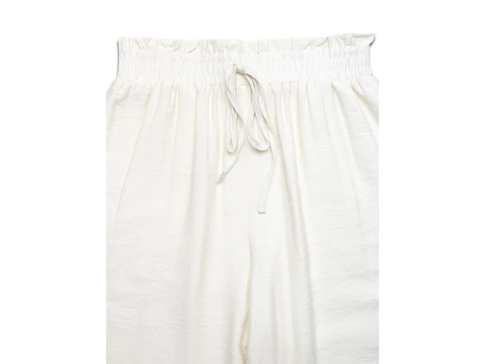 Close-up of the elastic waistband and drawstring on the white pants.