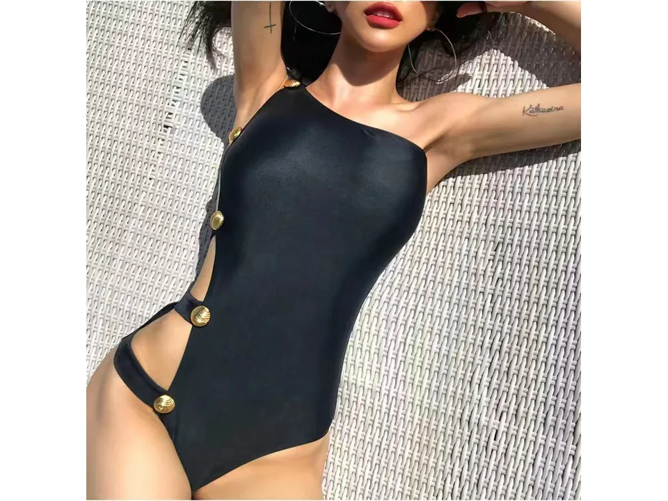 Close-up of the black one-shoulder swimsuit showing the side cutout and gold buttons.