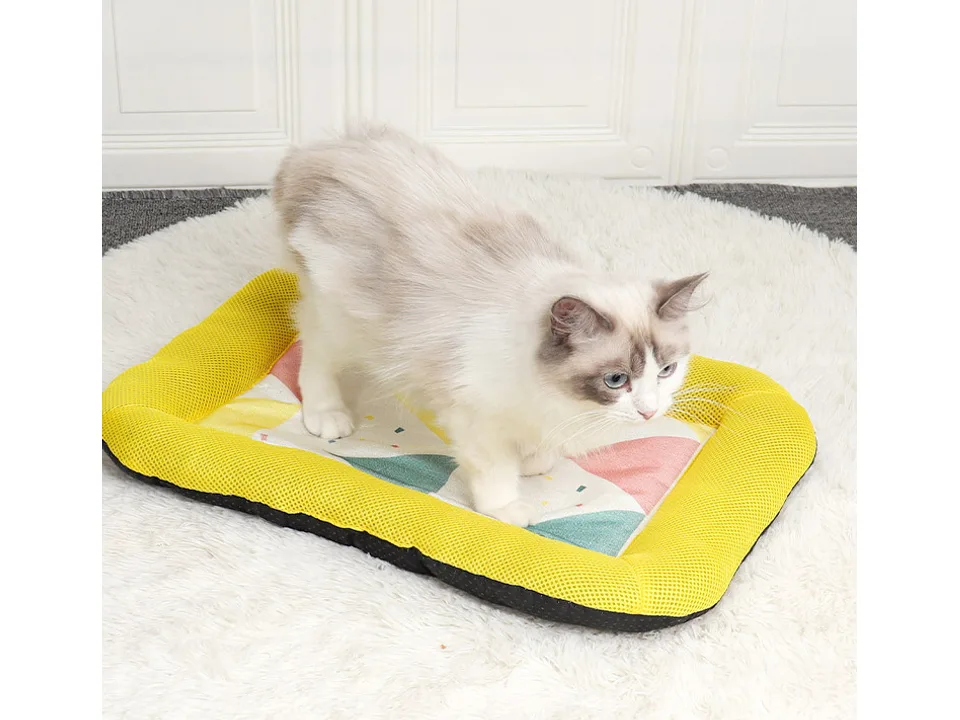 A cat standing on the yellow pet cooling mat.