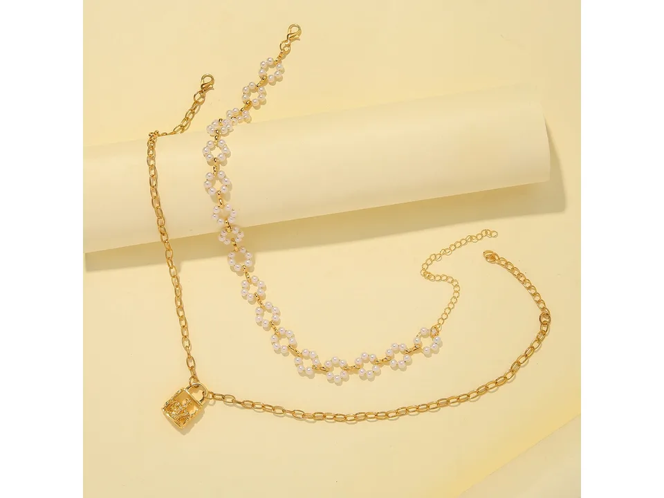 The layered pearl and crown lock necklace laid out flat.