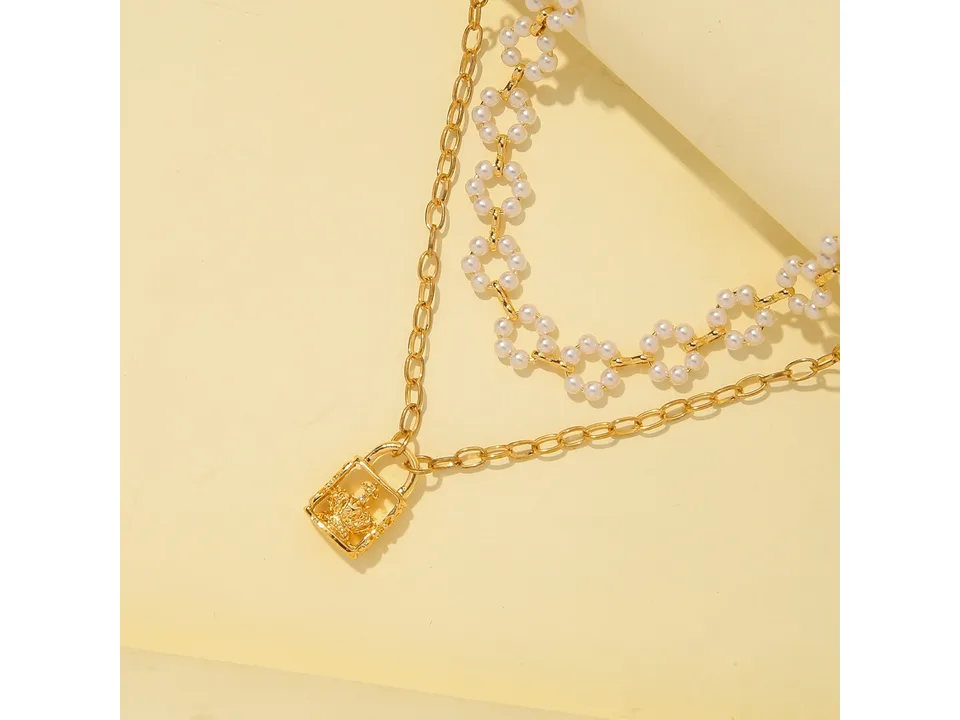 Close-up of the layered pearl and crown lock necklace on a light background.