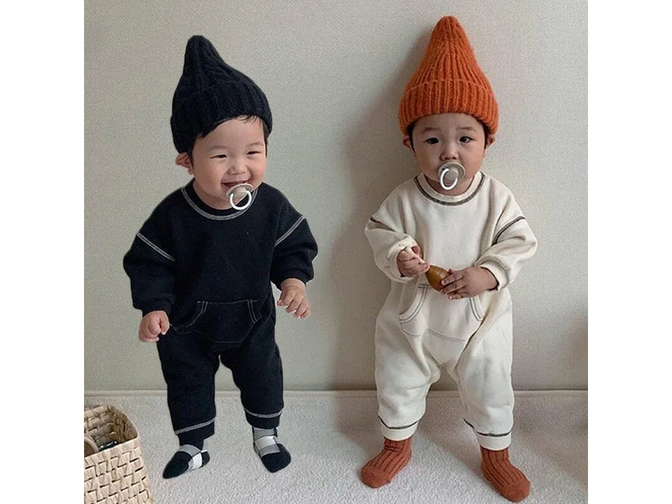 Two babies wearing the long sleeve rompers in black and white.