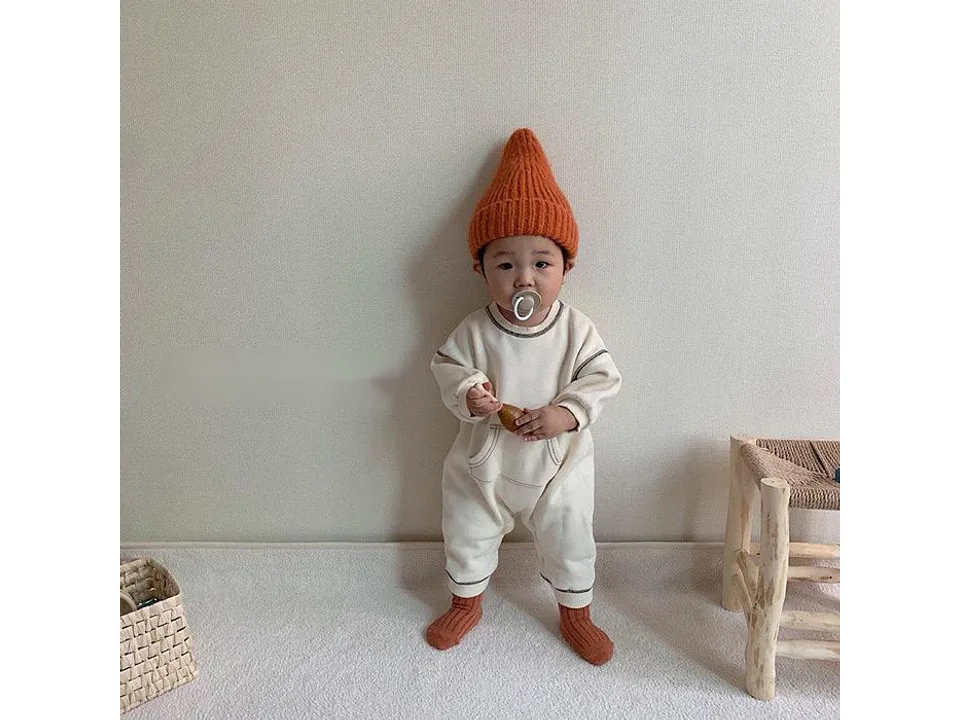 A baby wearing the white long sleeve romper with contrast stitching.