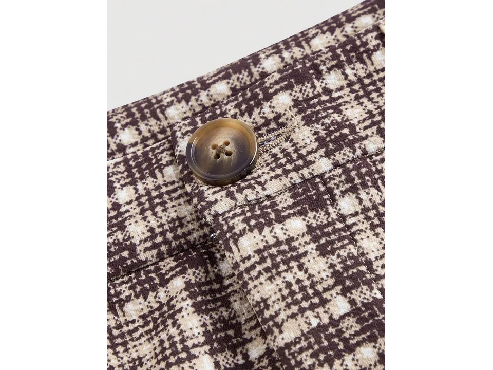 Close-up of the button and plaid fabric texture on the trousers.