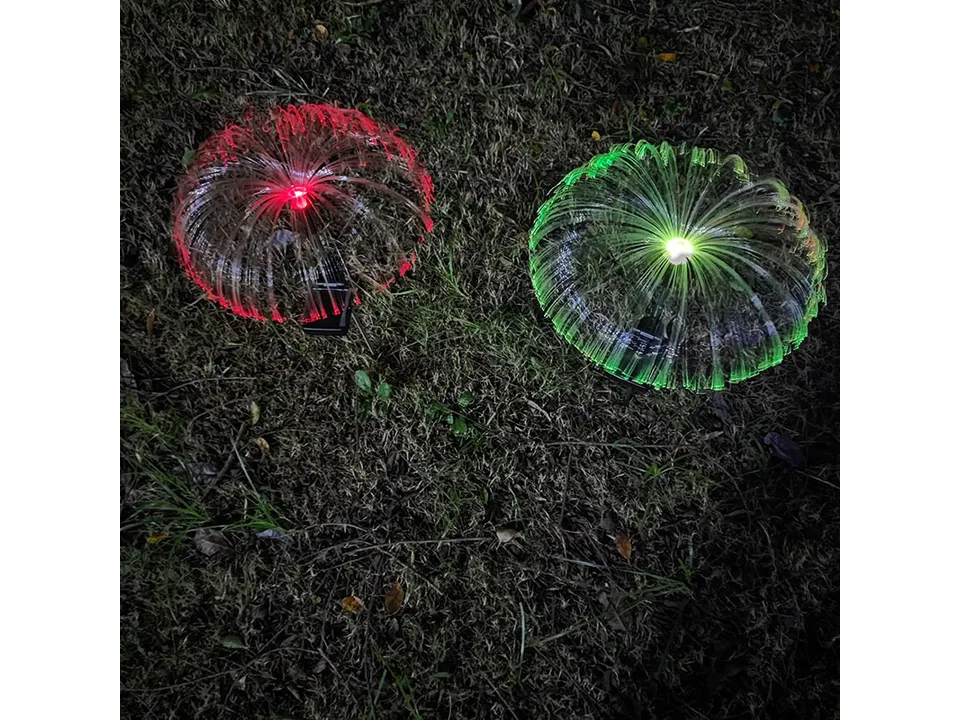 Two solar jellyfish lights in red and green glowing on the grass.