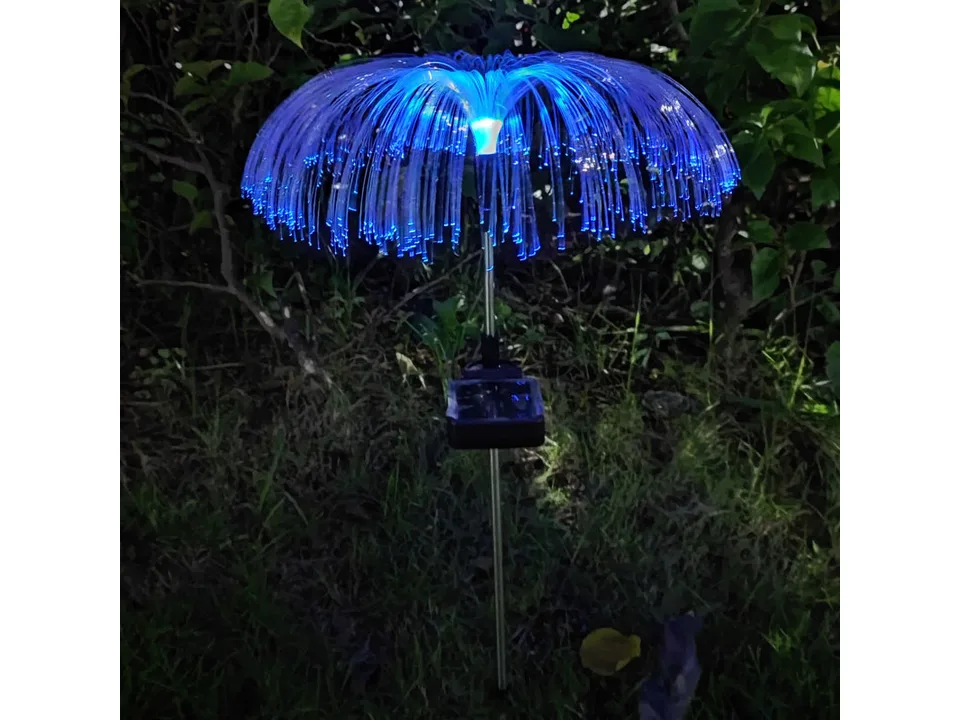 A blue fiber optic jellyfish garden light glowing in the dark.