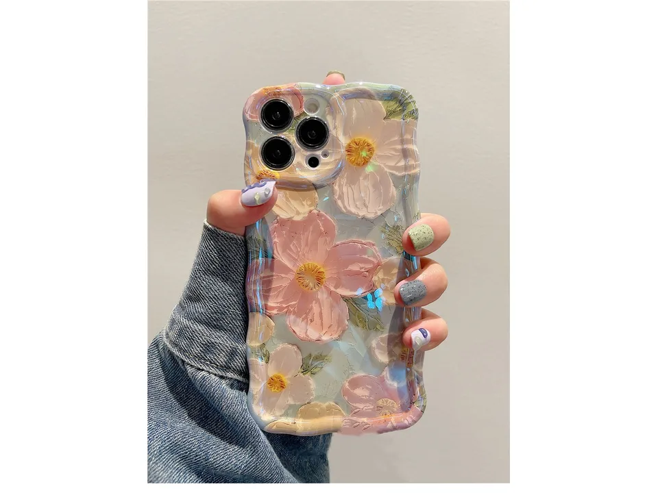 A hand holding a phone case with a pink and white floral oil painting design.