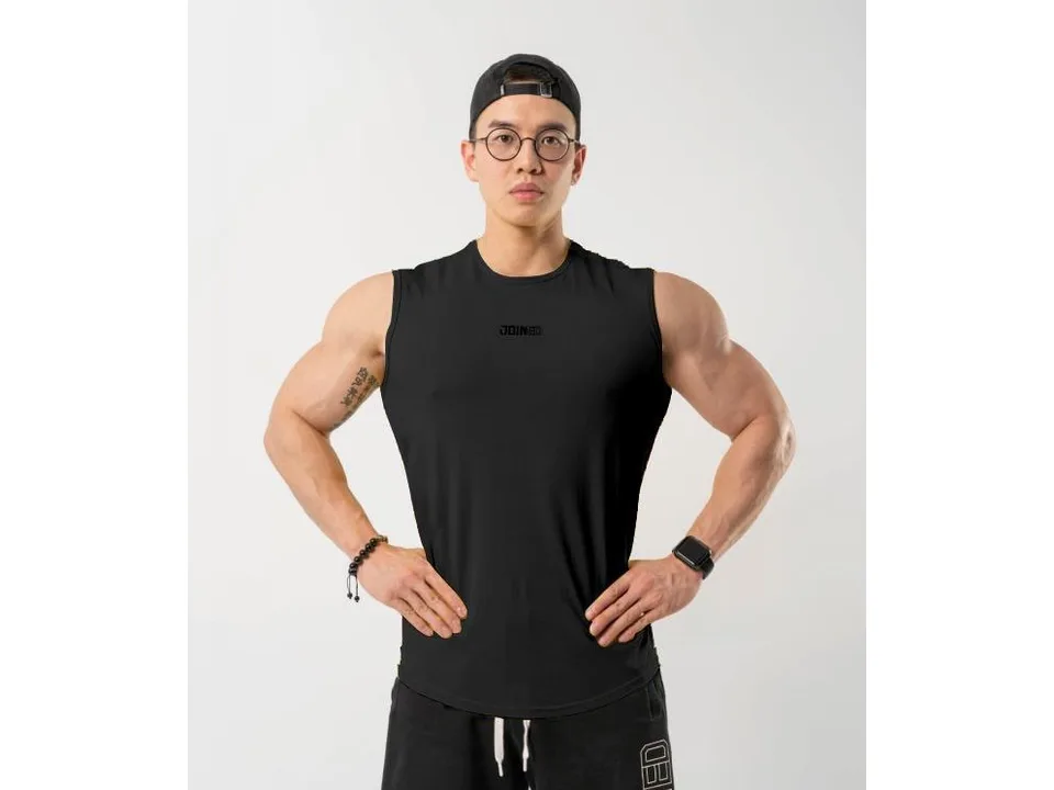 A man wearing a black sleeveless tank top against a plain background.