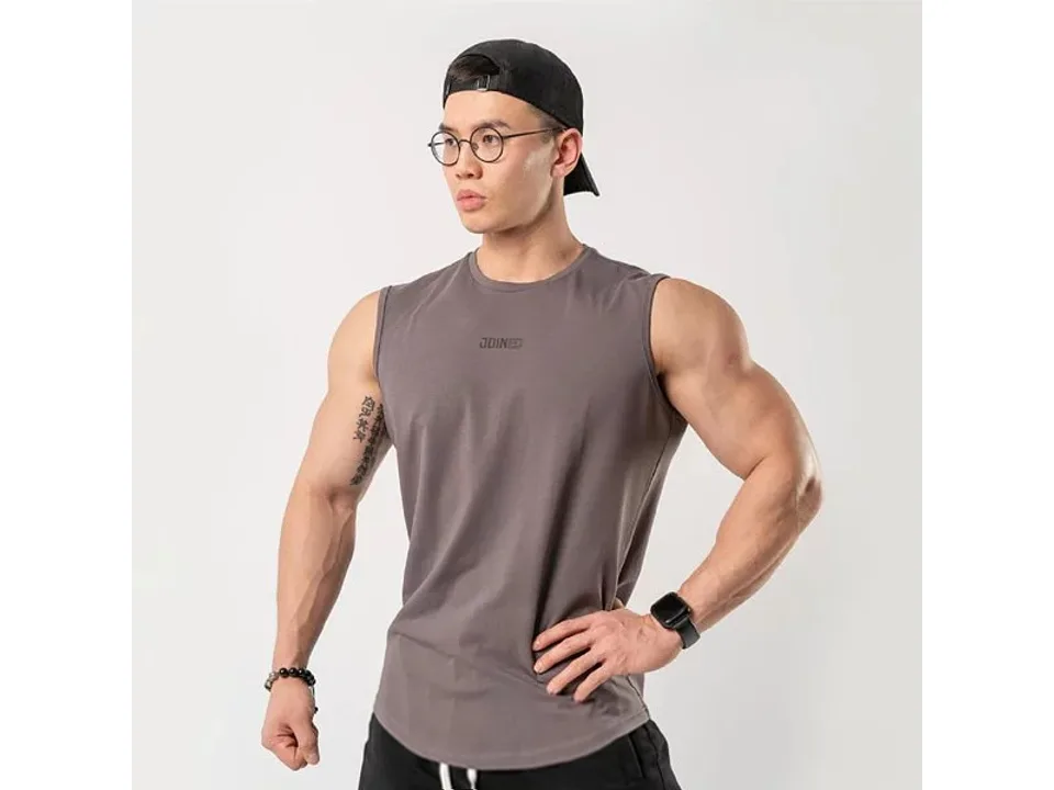 A man wearing a grey sleeveless tank top against a plain background.