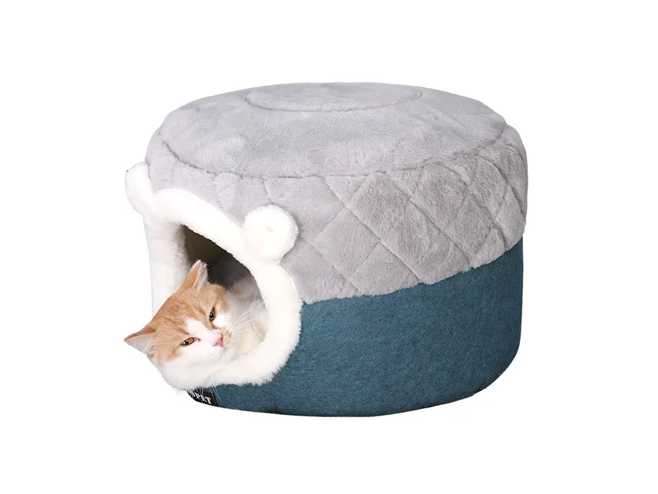 A cat resting inside the grey and blue plush pet cave bed.