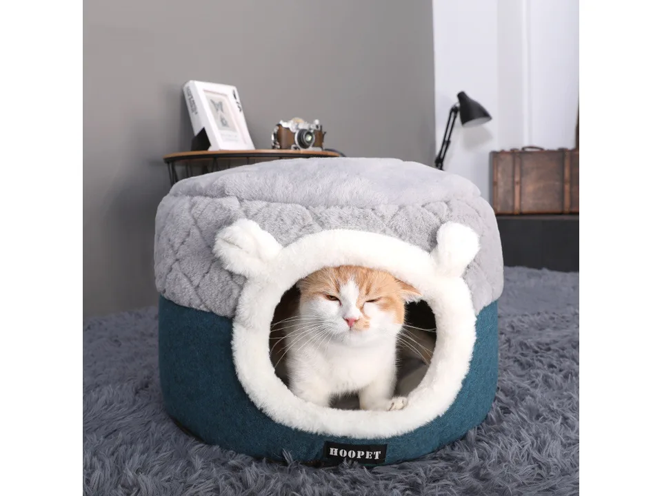 A cat sitting inside the grey and blue plush pet cave bed.