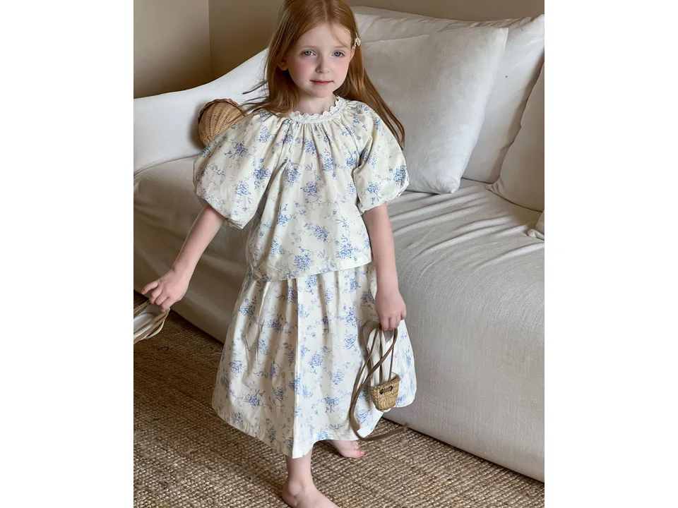 A young girl standing in a floral cotton skirt set.