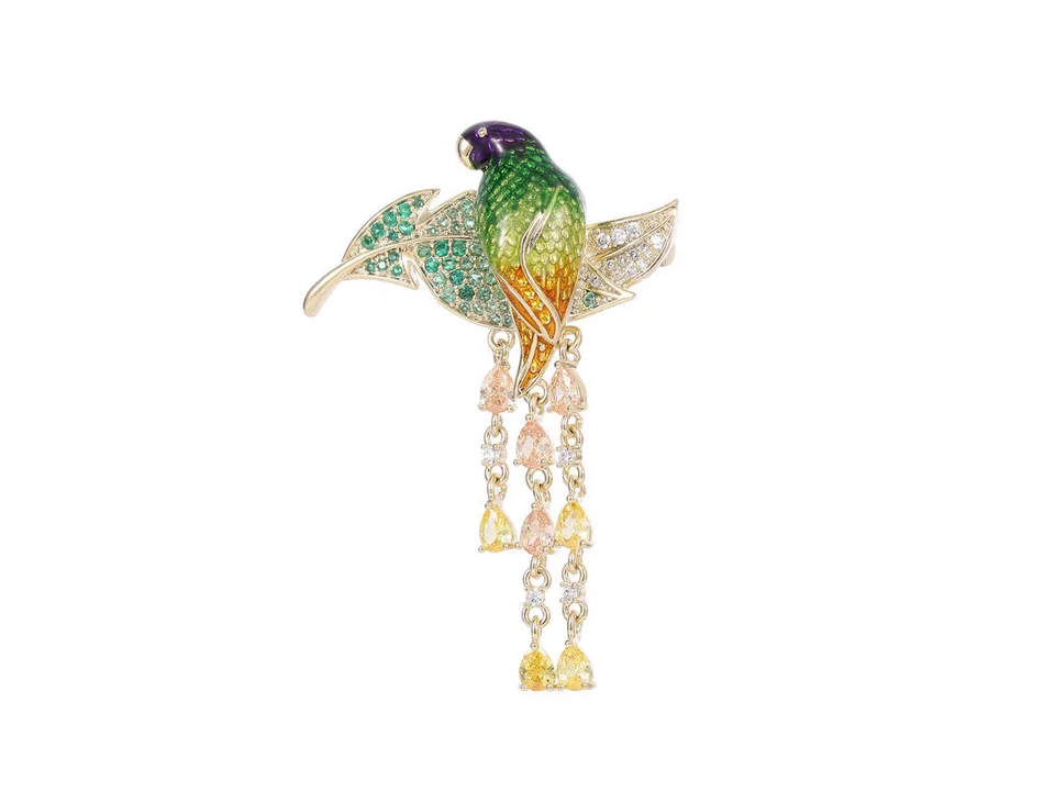 Parrot brooch with green, yellow, and clear crystals on a white background.