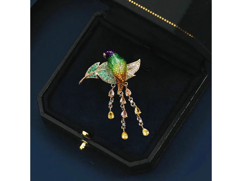 Parrot-shaped brooch with colorful crystals inside a black jewelry box.