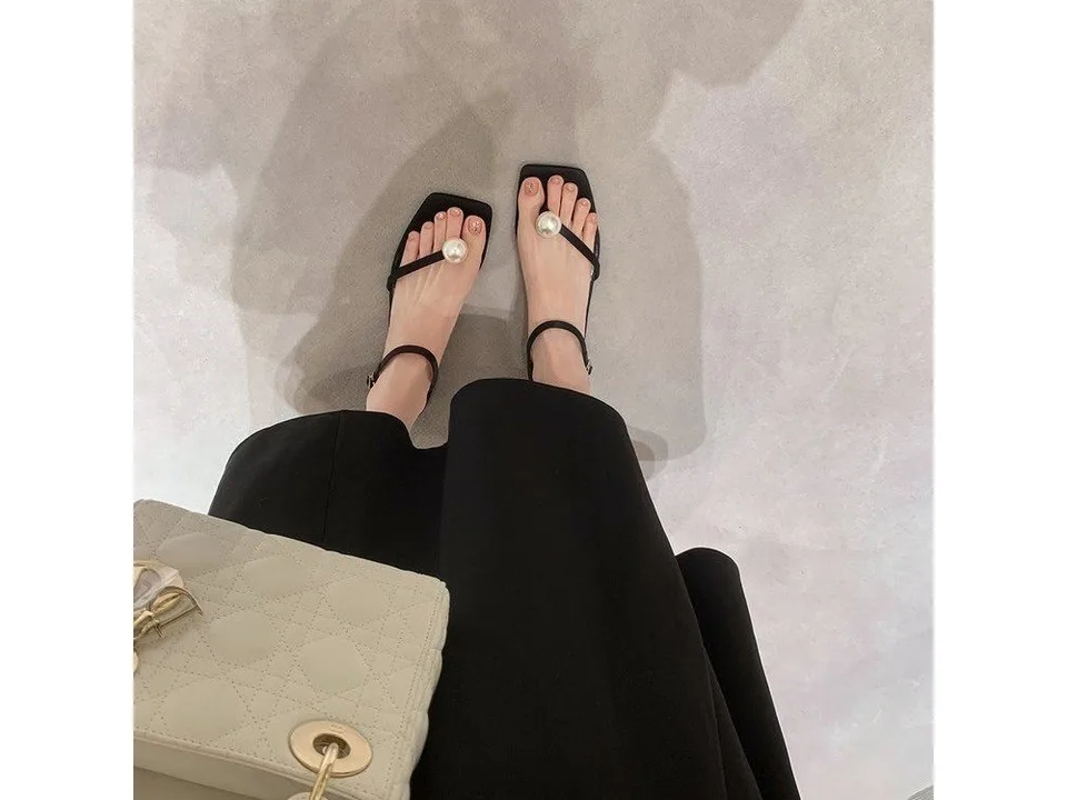 Top-down view of a person wearing the black pearl sandals.