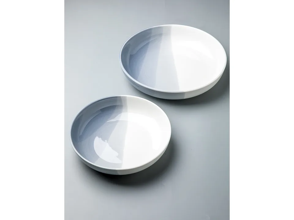 Two blue and white ceramic bowls of different sizes on a grey surface.